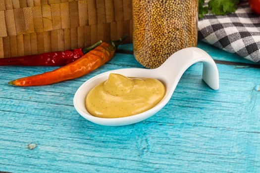 Spoon of mustard sauce on wooden table photo