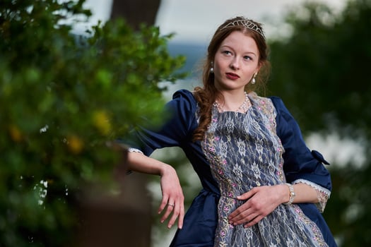 Portrait of a young long red hair girl in Victorian style dress posing beside castle photo