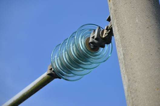 Glass Insulators on Power Line Against Blue Sky photo