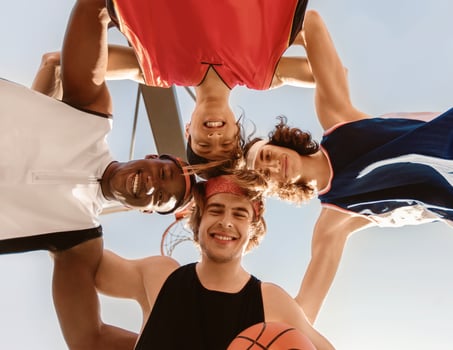 Smiling basketballers putting their heads together in unity outdoors, bottom view photo