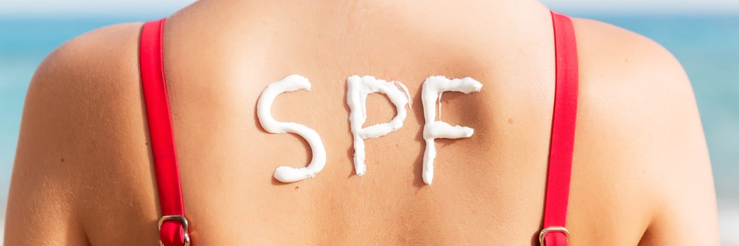 SPF word made of sunblock at woman's back at the beach. Sun protection factor concept photo