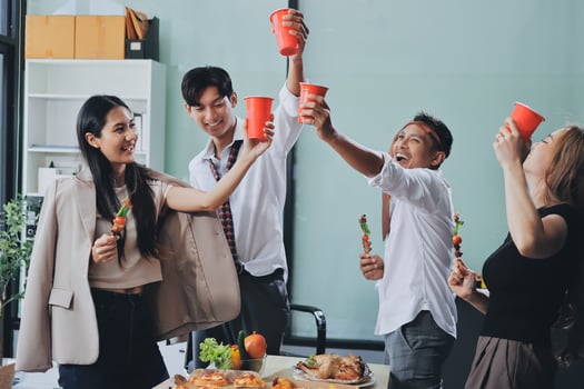 Happy asian business people toasting with red cups at office party photo
