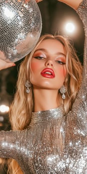 A woman in a silver dress holding a disco ball. photo