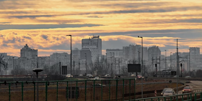 The photograph captures a stunning urban landscape at sunset, featuring a distant city skyline with high-rise buildings bathed in golden light. photo