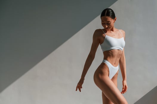 Standing against ,the wall and showing body. Young caucasian woman is indoors in the studio photo