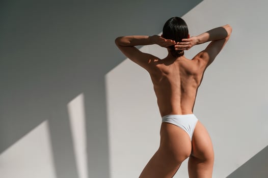 Rear. view.. Young caucasian woman with slim body shape is indoors in the studio photo