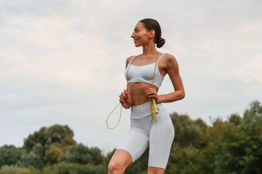 Holding jumping, rope. Young caucasian woman with slim body shape is in the fitness clothes outdoors photo