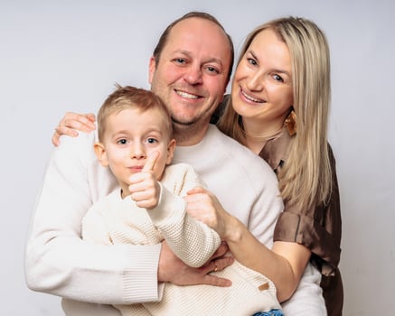 European happy family with son 4 years old, studio shot waist-high, dressed in beige colors on white background, all blond parents 35-39 years old, boy shows a finger in the air photo