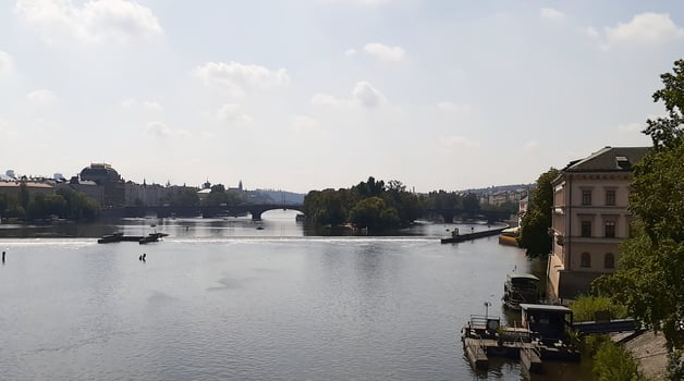 City river on a cloudy summer day calm water surface reflects gray clouds and greenery of embankments photo