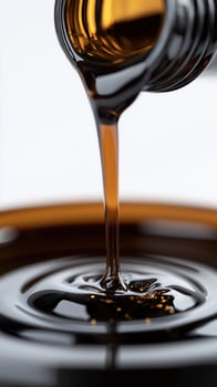 Close-up of thick dark syrup pouring from bottle into a shiny metal container photo