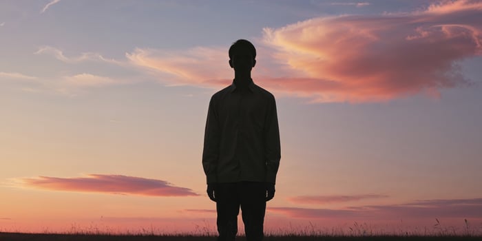 Silhouette of a man standing in a field at sunset. photo