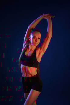 Stretching ,the, hands. Beautiful muscular woman is indoors in the studio with neon lighting photo