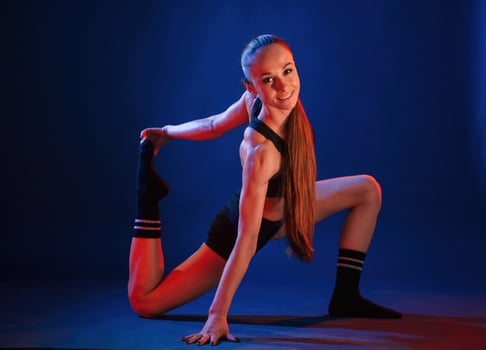 Doing sportive, exerises. Beautiful muscular woman is indoors in the studio with neon lighting photo