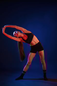 Warm, up exercises. Beautiful muscular woman is indoors in the studio with neon lighting photo