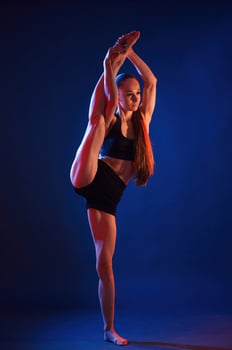 Raising up ,the leg, exercise. Beautiful muscular woman is indoors in the studio with neon lighting photo
