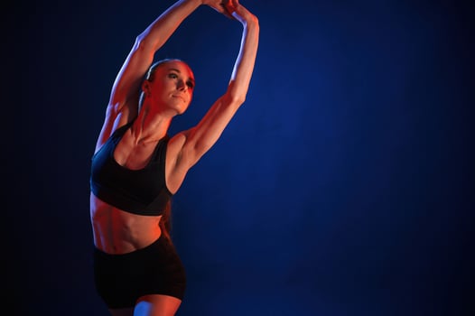 Fitness exercises. Beautiful muscular woman is indoors in the studio with neon lighting photo