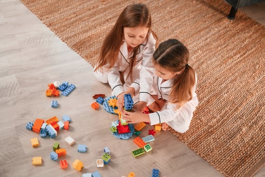 View, from the top.. Playing construction game. Two little girls are having fun together in domestic room photo