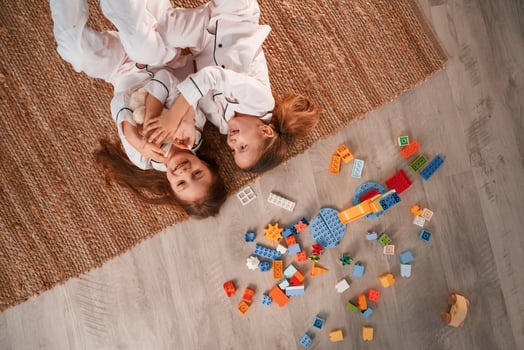 Top view. .Lying down.. Construction plastic toys. Two little girls are playing and having fun together in domestic room photo