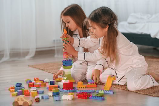 Many of the ,blocks of plastic construction toys. Two little girls are playing and having fun together in domestic room photo