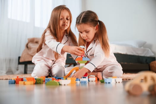 Toys, are ,on the floor. Two little girls are playing and having fun together in domestic room photo