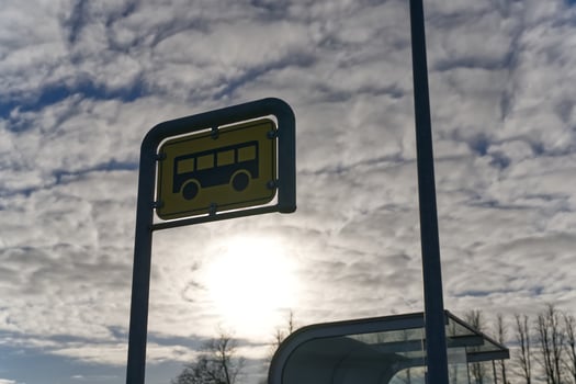 Silhouetted Bus Stop Sign Against Cloudy Sky photo