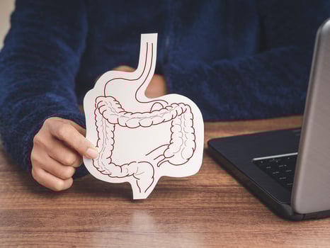 Close-up of hand holding a large intestine symbol made from yellow paper while sitting at the table. photo