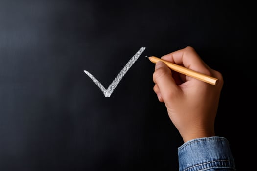 Teacher drawing check mark symbol on blackboard with chalk photo