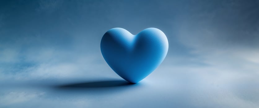 Blue heart rests on blue textured surface. photo