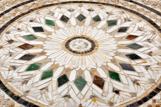 A circular mosaic tile with a flower design photo