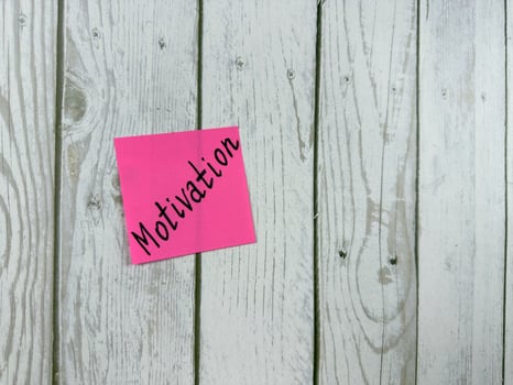 Sticky note with Motivation written on it, affixed to a white wooden board. Representing inspiration and drive, this image is perfect for concepts of personal growth and determination photo
