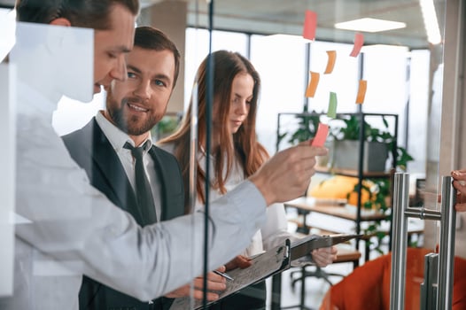 Group of ,coworkers in the office is standing together and putting stickers on the glass photo