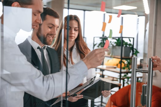 Group, of coworkers in the office is standing together and putting stickers on the glass photo
