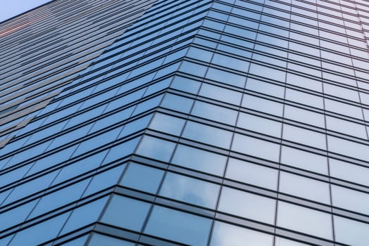 Modern building glass walls with sky and cloud reflection. Blue business background. photo