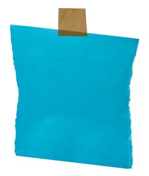 A ripped blue paper sheet with rough edges, secured by beige adhesive tape at the corners, copy space photo