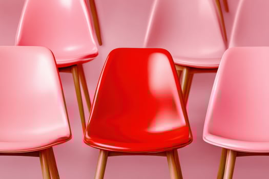 Rows of blush-pink chairs with a striking red accent seat creating a bold minimalist contrast in a modern seating arrangement photo