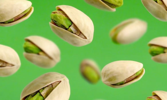 Falling pistachios on a green background, the benefits of nuts for the body photo