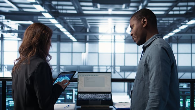 Programmers using AI technology on laptop and tablet in data center employing machine learning models. Devices used by artificial intelligence experts in server farm, camera B photo