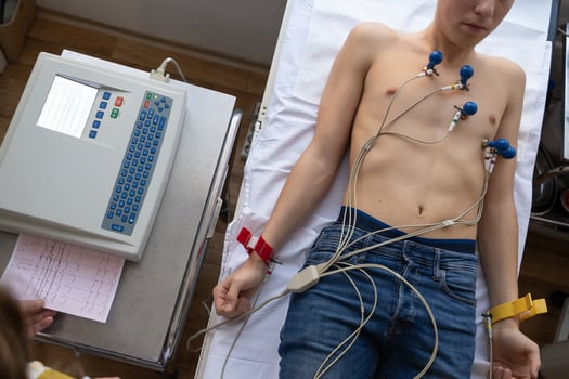 A female doctor performs an ECG on a young man in a hospital room, carefully monitoring his heart health during a routine checkup. photo