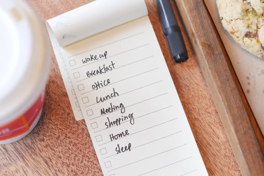 Daily to-do list with breakfast items and coffee on wooden table photo