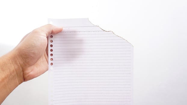 Hand holding stripped paper burns edge isolated on a white backgrounds photo