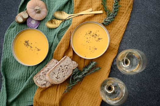 An intimate dining scene featuring golden pumpkin soup, fresh sourdough bread, and elegant wine glasses. photo