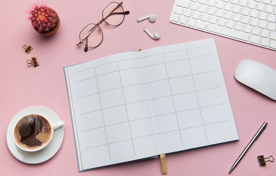 Open notebook, coffee, cactus, glasses, earphones, pen, keyboard and mouse lying on pink table photo