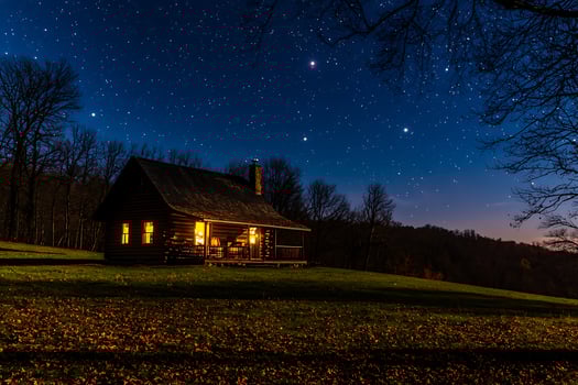 Illuminated Log Cabin Under a Starry Night Sky. A picturesque scene of a cozy cabin glowing warmly against the backdrop of a breathtaking celestial display. photo