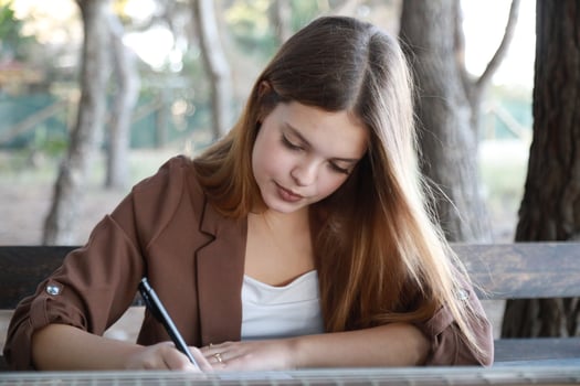 Women Writes Music Notes On Sheet Music Sitting At The Park Table In The Nature photo
