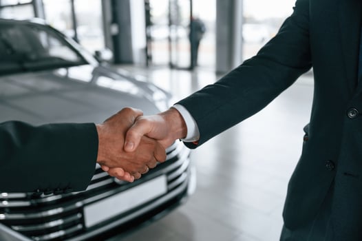 Two businessmen are, standing in the car showroom and making a deal, handshake photo