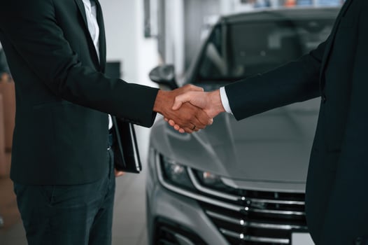 Close ,up view. Two businessmen are standing in the car showroom and making a deal, handshake photo