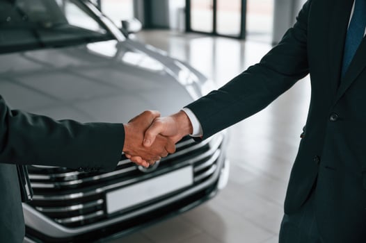 Close up view. Two businessmen are standing in ,the car showroom and making a deal, handshake photo