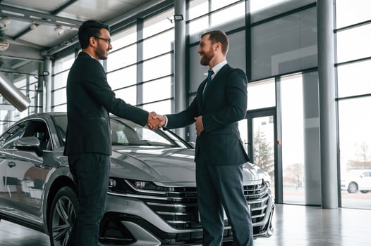 Doing handshake. Man is consulting the customer in the car showroom photo