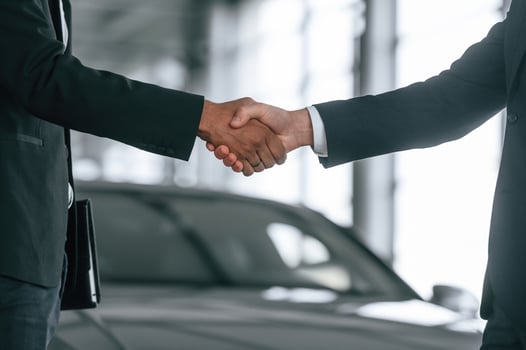 Close up view. Two, businessmen are standing, in the car showroom and making a deal, handshake photo