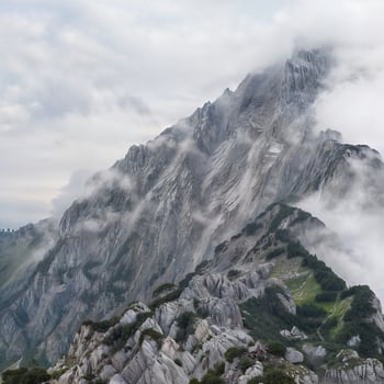 The hostile landscape of the great mountains, the peaks of which are densely covered with a dark fog. photo